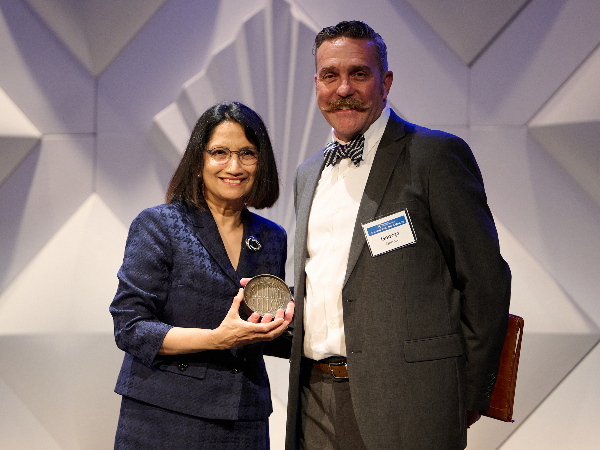 President Neeli Bendapudi and George Garrow pose for a photo on stage with the Alumni Fellow Award