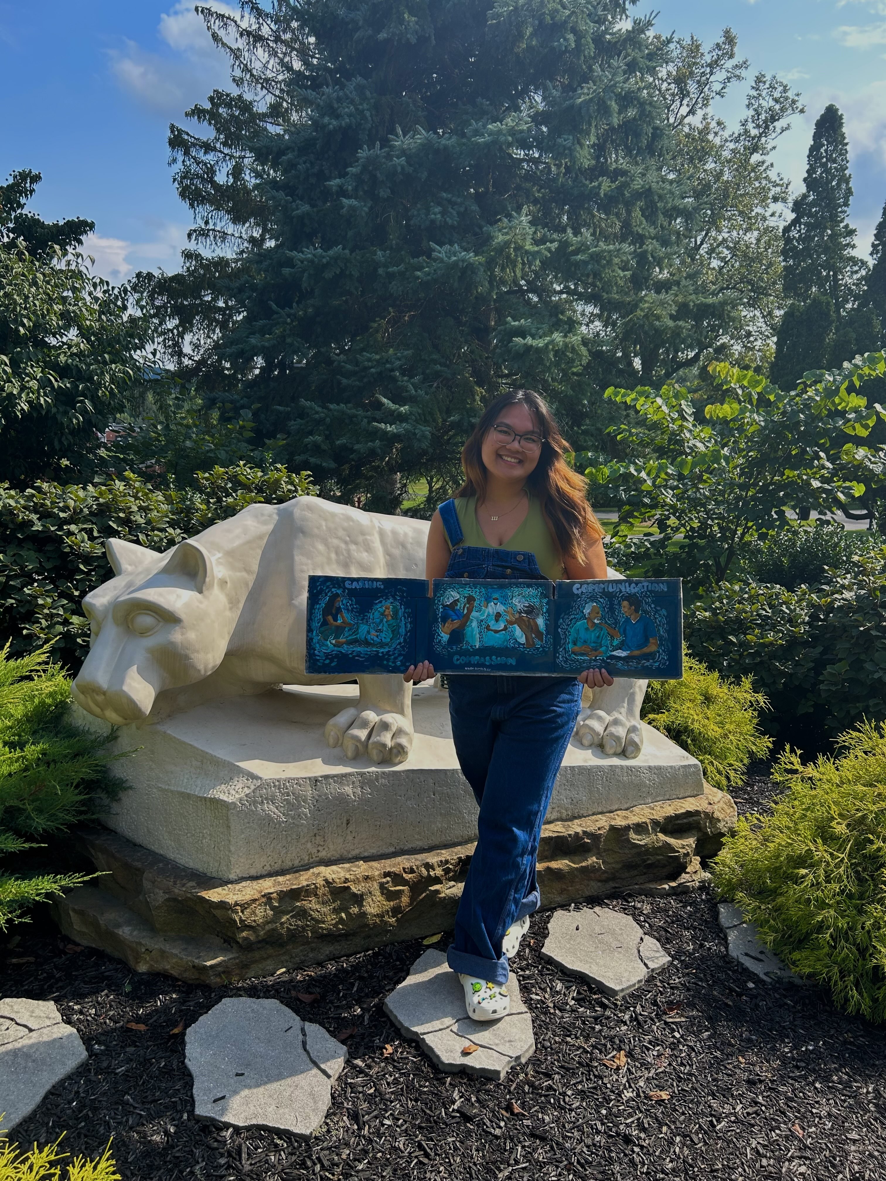 Person holding artwork in front of the Lion Shrine. 