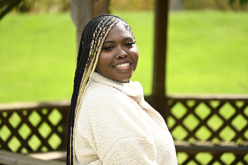 A student seated outside and looking over her shoulder at the camera.