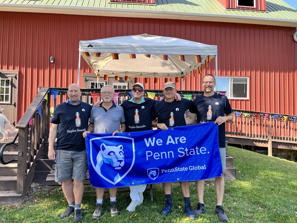 A group of alumni posing with a "We Are Penn State" banner