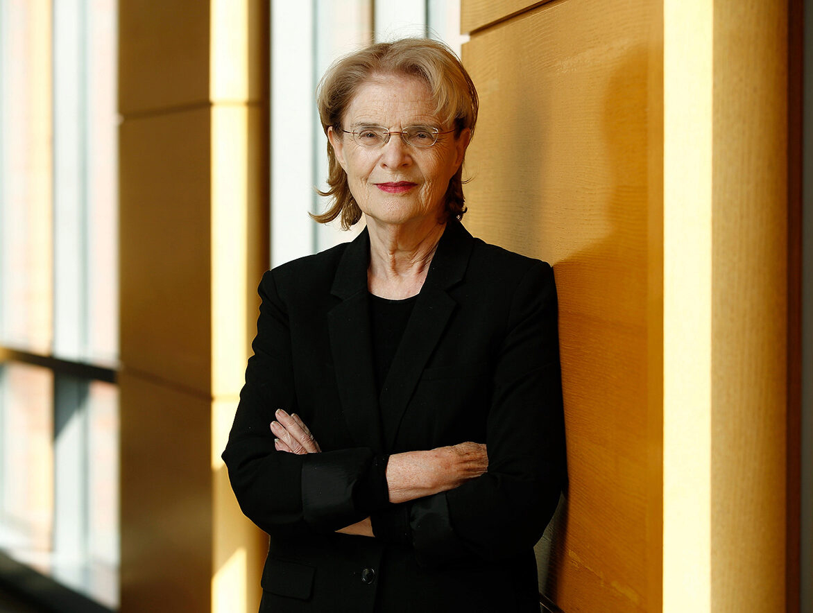 A photo of Susan Wachter with her arms crossed, leaning against a wall.