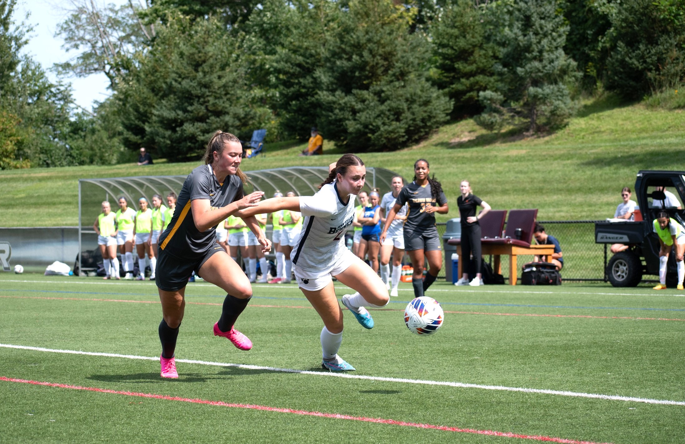 A Penn State Behrend women's soccer player runs past a defender.