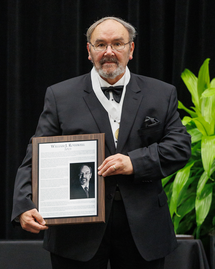 William Rothwell holds a plaque denoting his induction into the Hall of Fame.