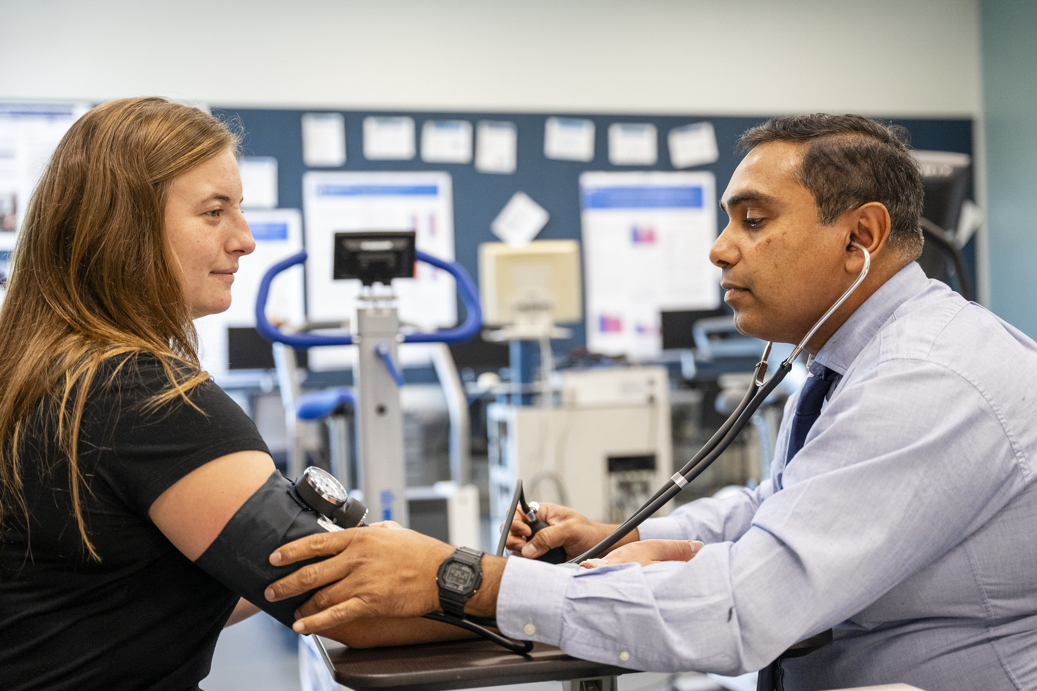 One person wearing a stethoscope takes the blood pressure of another person