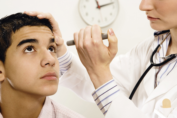 A doctor examines a young man's eyes