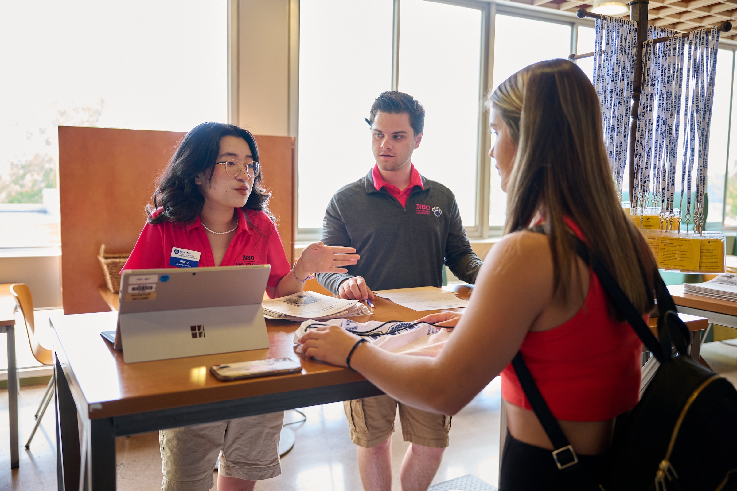 Two student orientation leaders at a check-in table helping a new student