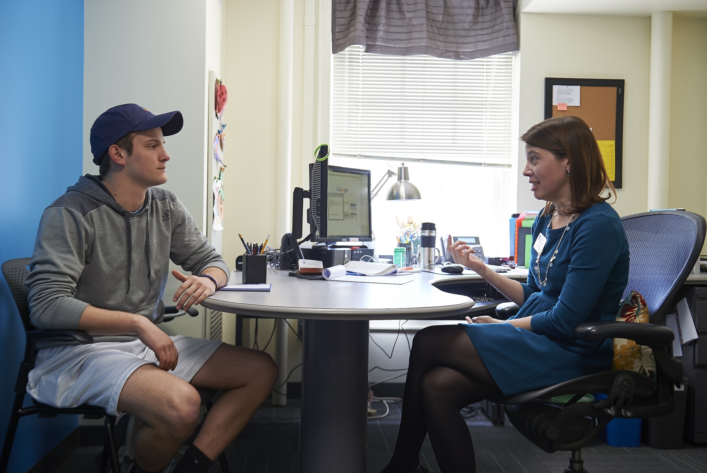 Students sitting across a desk talking with an academic adviser