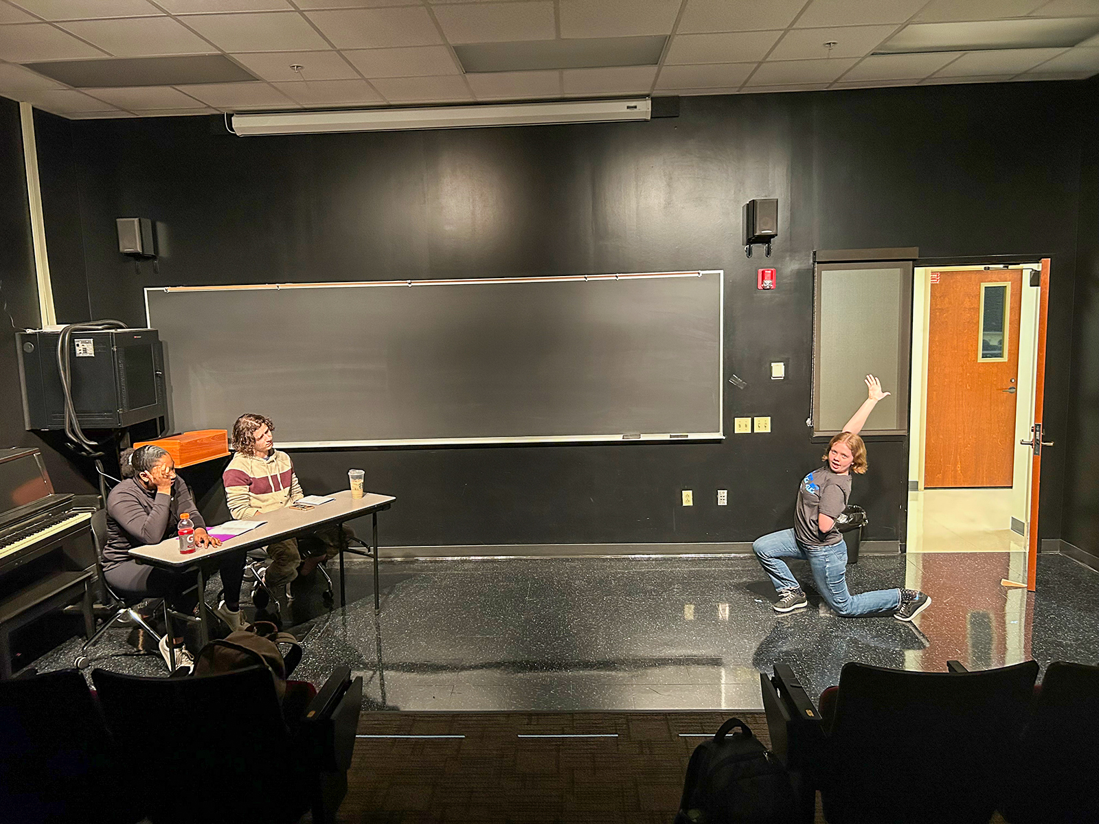 Male and female student at a table, other female student appearing to dance