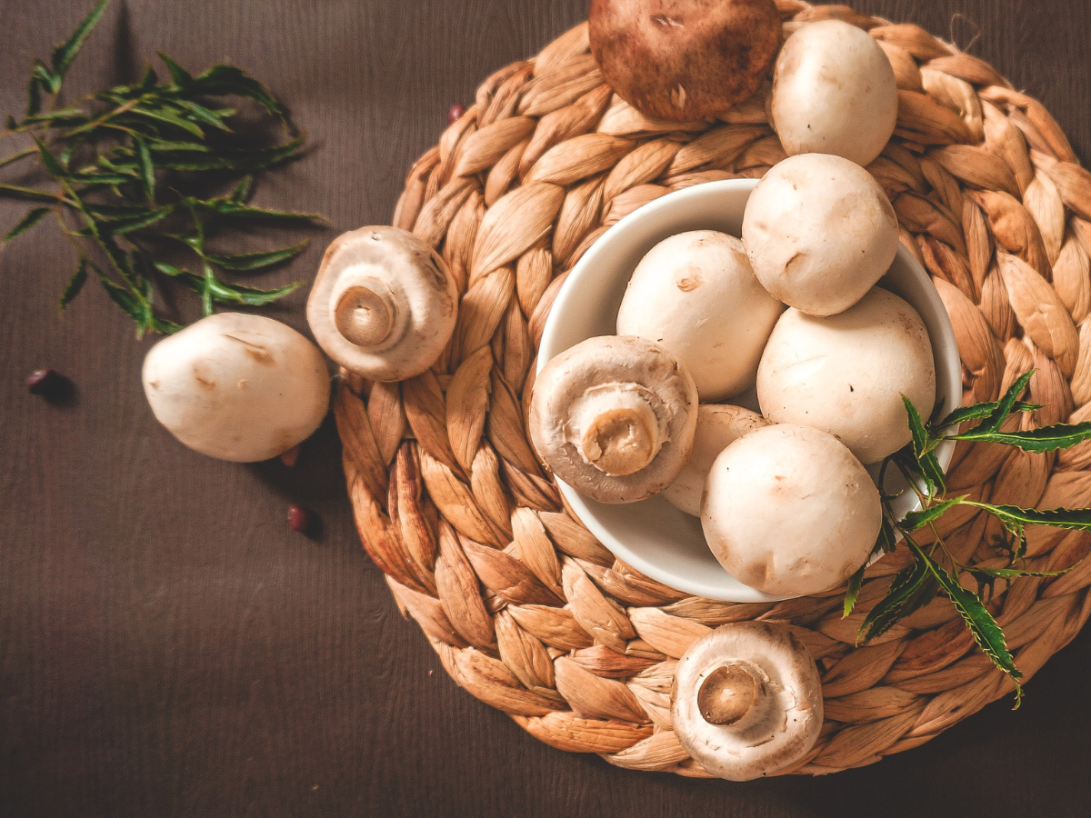 Button mushrooms in a wicker basket on a table