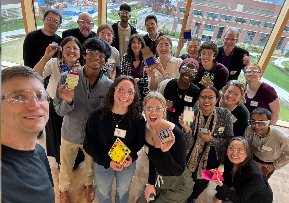 A group photo of people smiling and holding up small projects. 