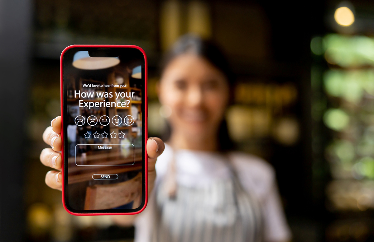 Waitress displays an app to rate an experience at a restaurant