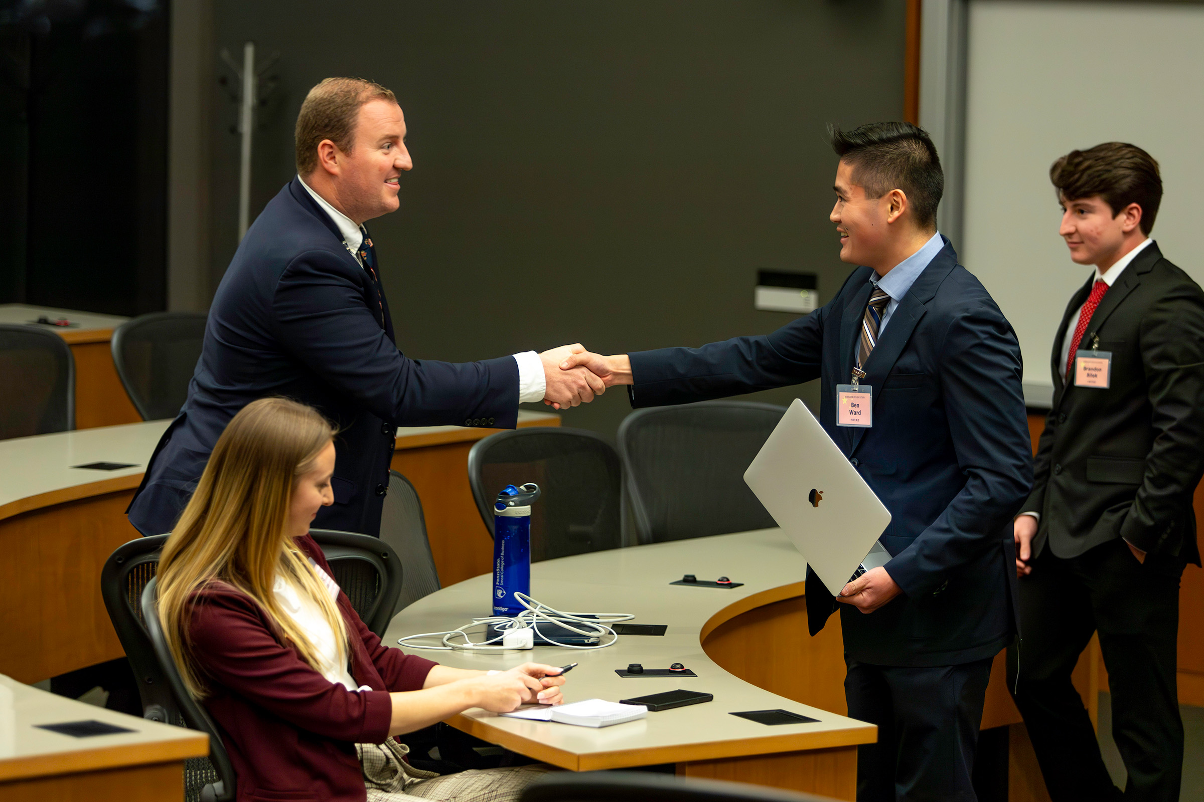 SIA students Barrett Beaumont (left - Team United States) and Ben Ward (Team China) shake hands while negotiating during the USAWC crisis simulation.