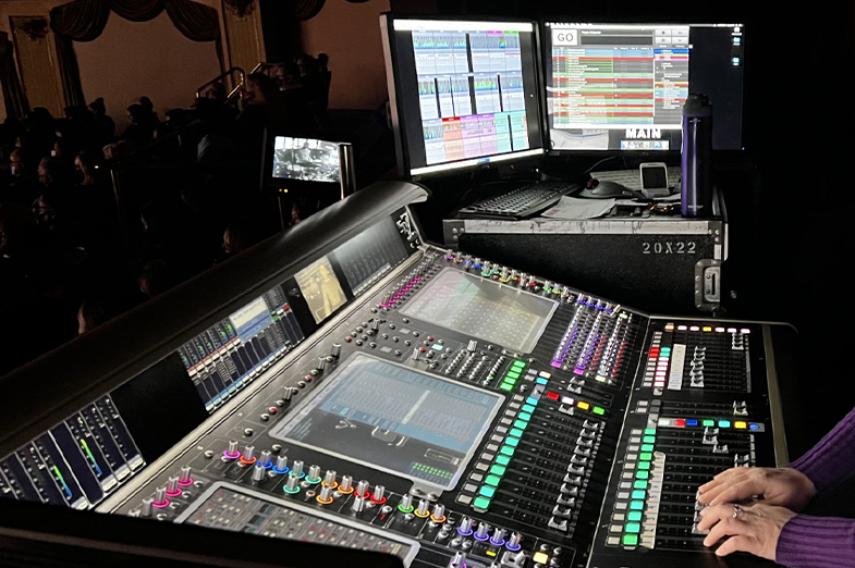 Theater production sound board with hands on knobs