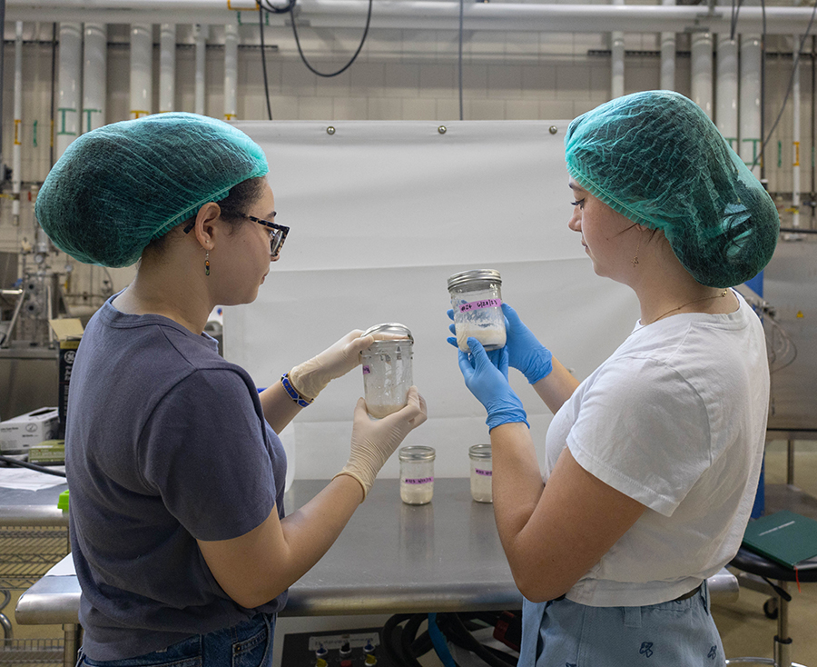 Two researchers with hair nets holding up sour dough starter