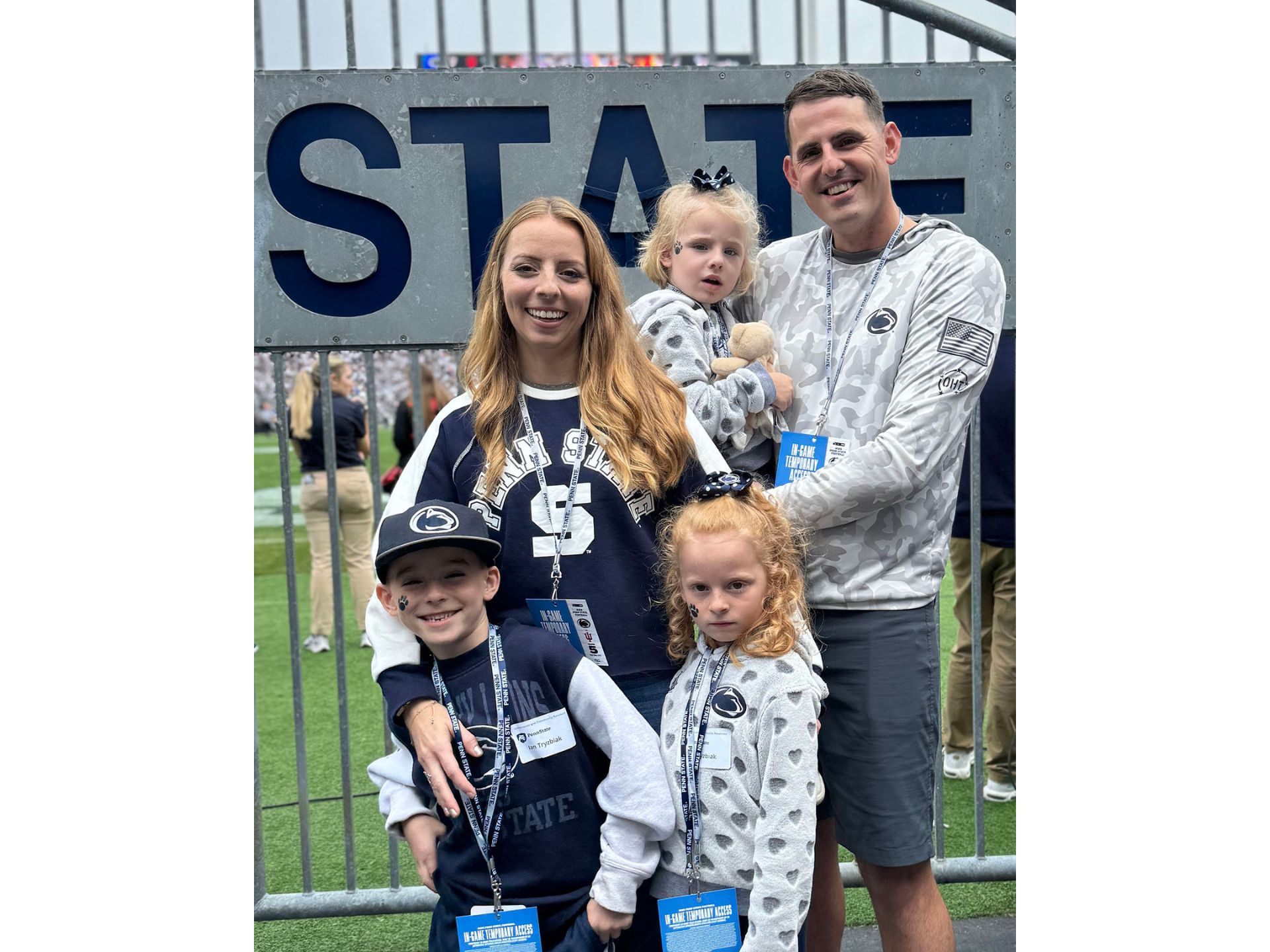 A man, woman and three children pose together in front of a gate.