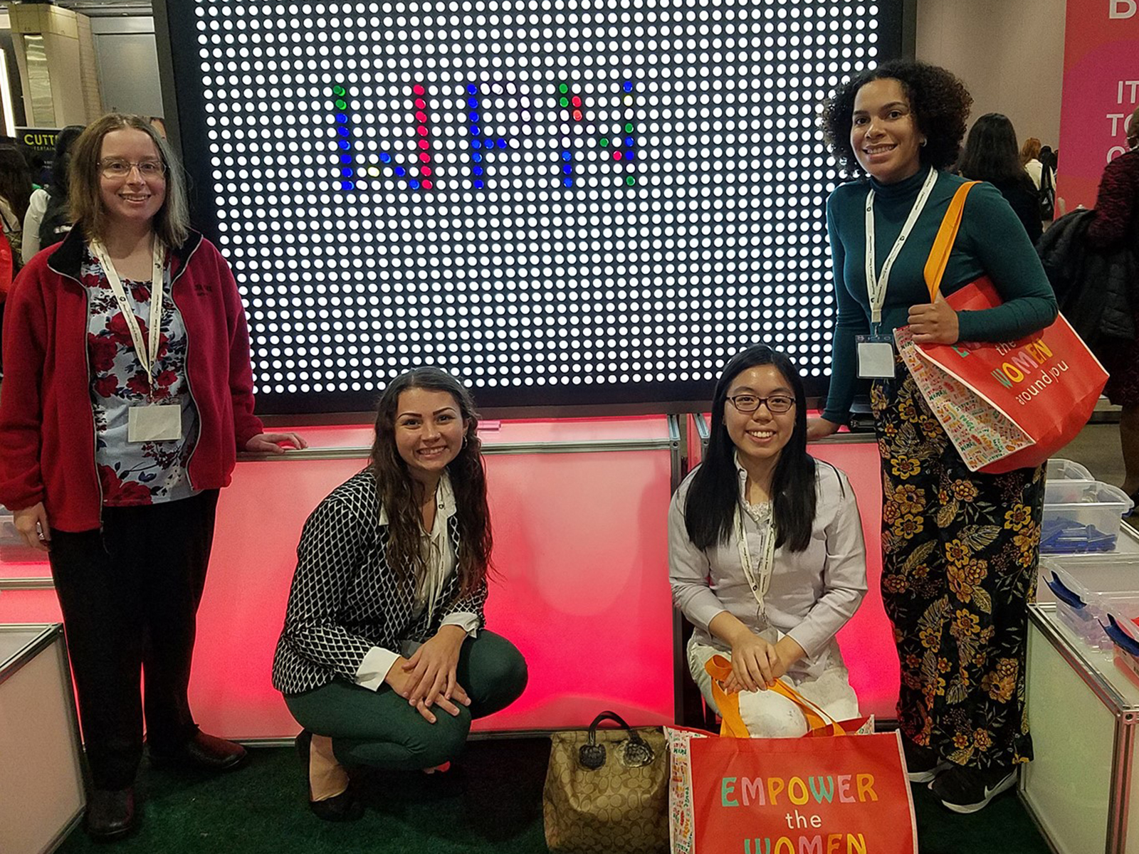 Four young women in front of a light board