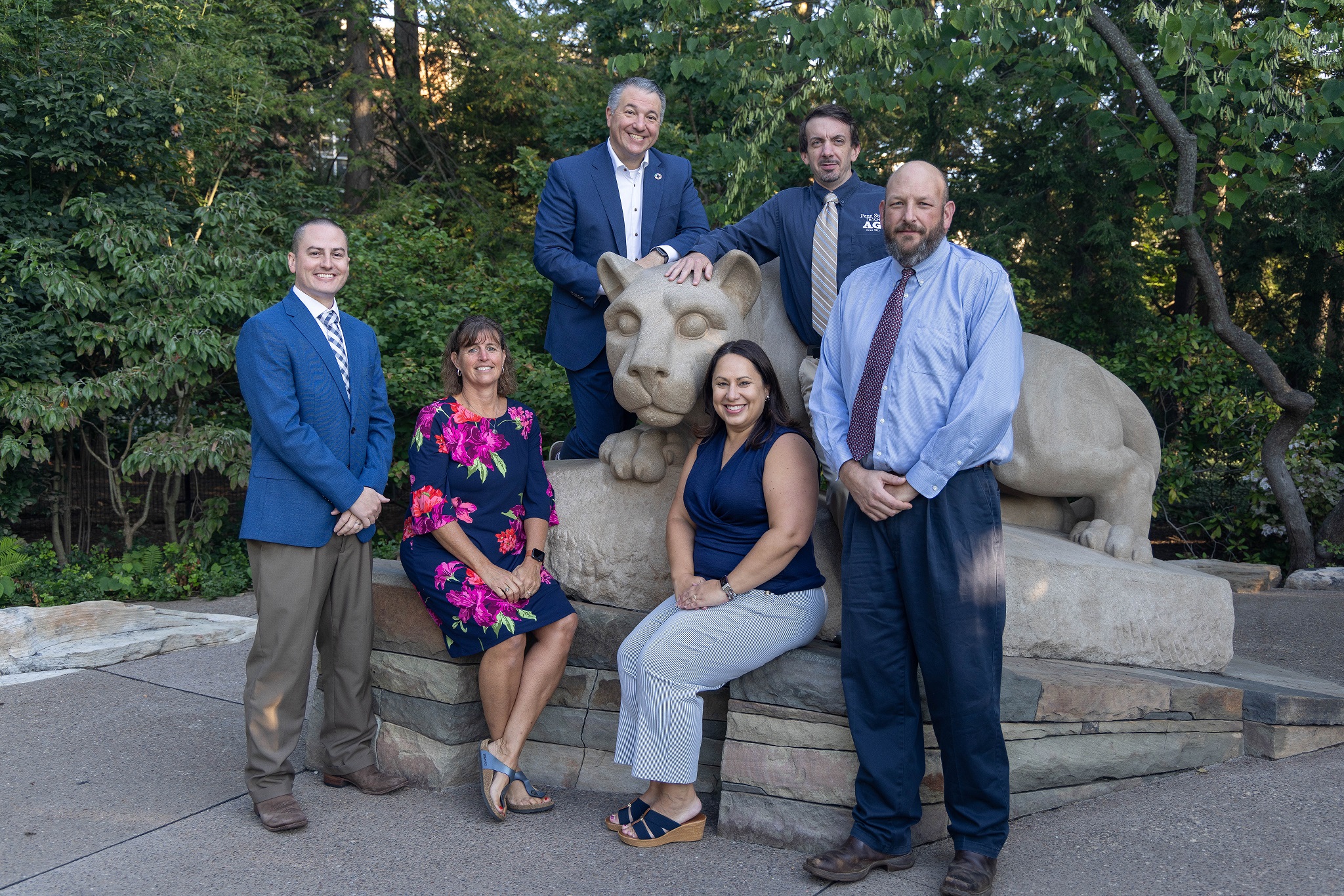 Six people posing with the lion shrine.