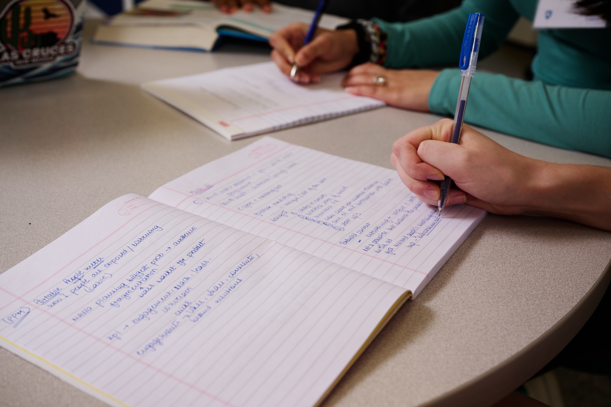 Person writing in notebook using a pen