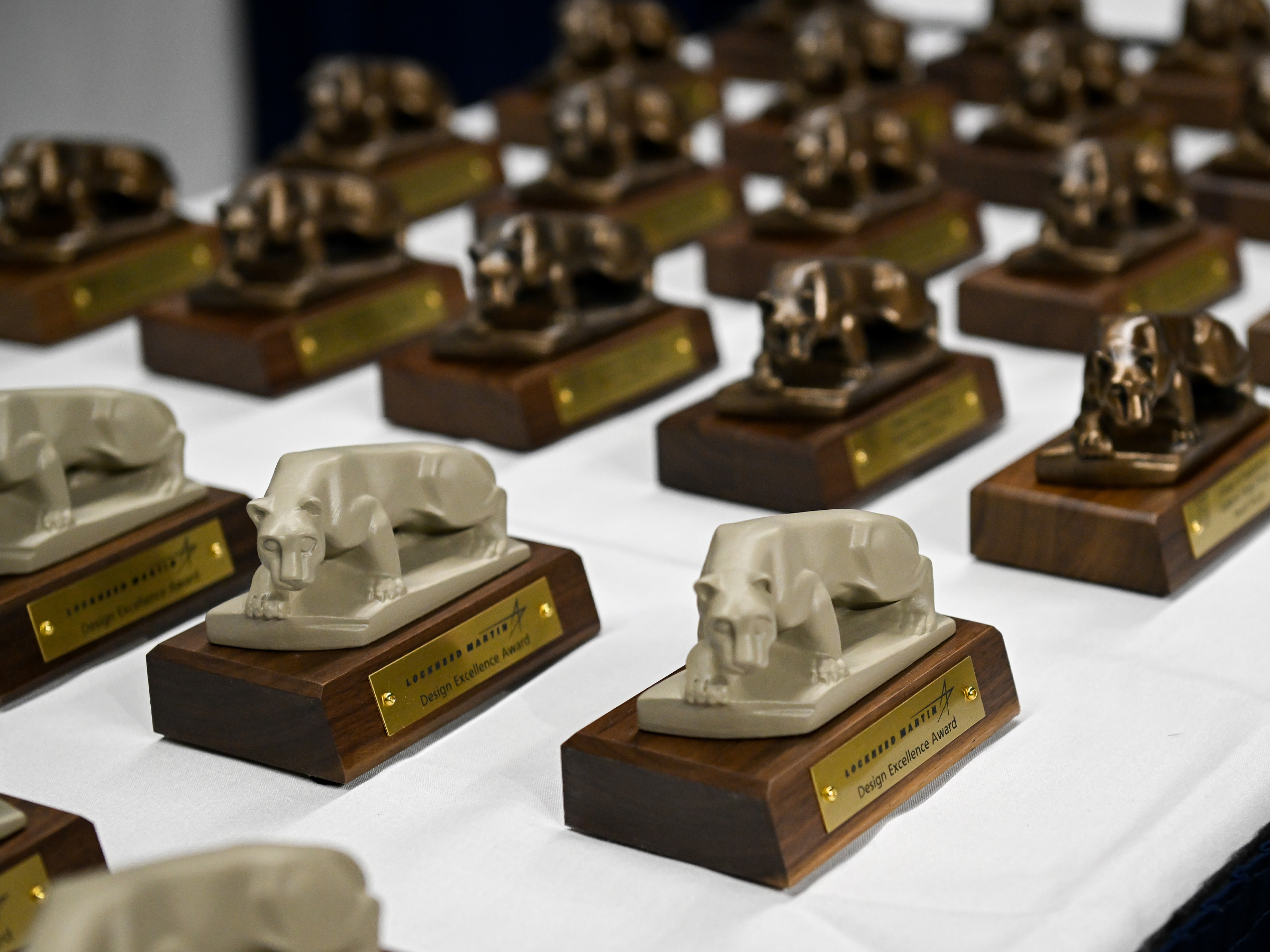 Trophies depicting the Nittany Lion are arranged on a table.