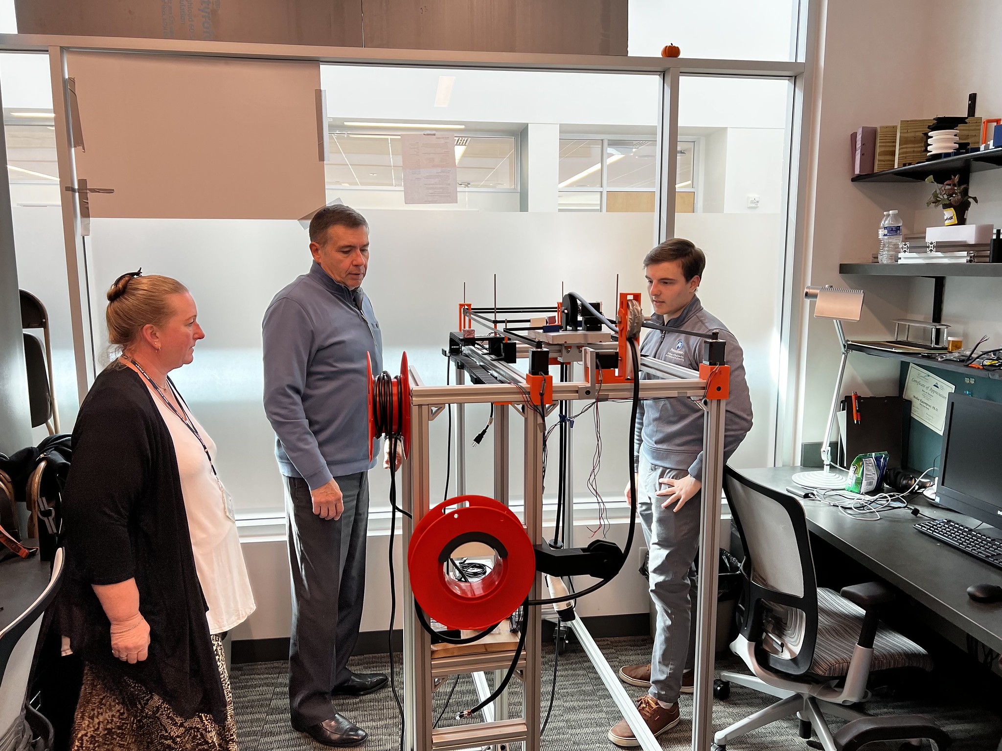 Three people view technological prototype