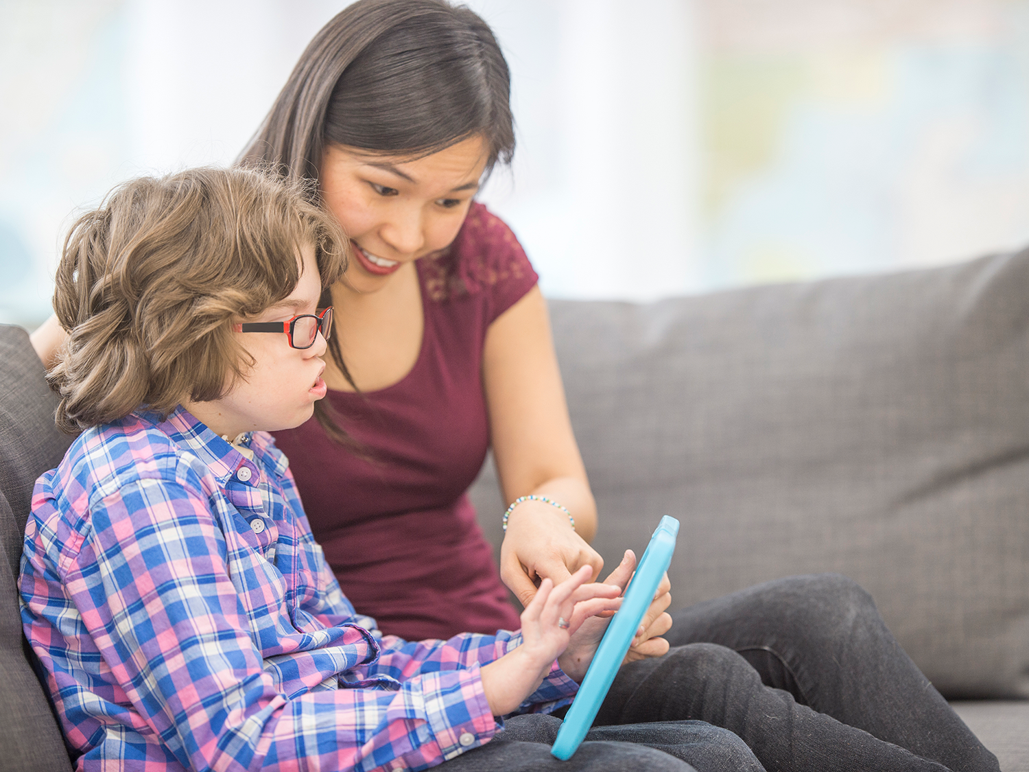 Tutor teaching a child with educational games on a tablet.