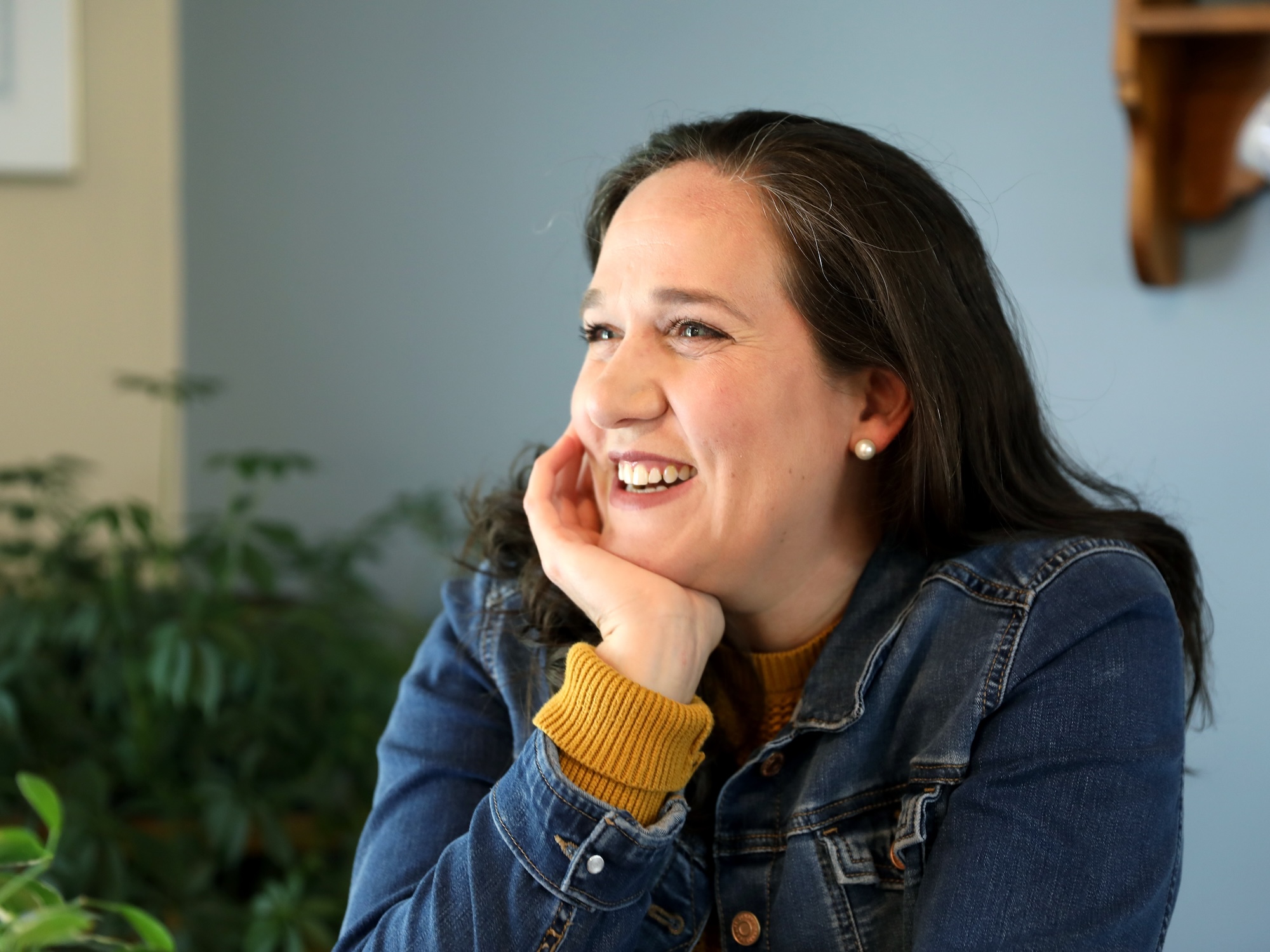 Headshot of Heather Holleman wearing a jean jacket, smiling, with her hand on her chin