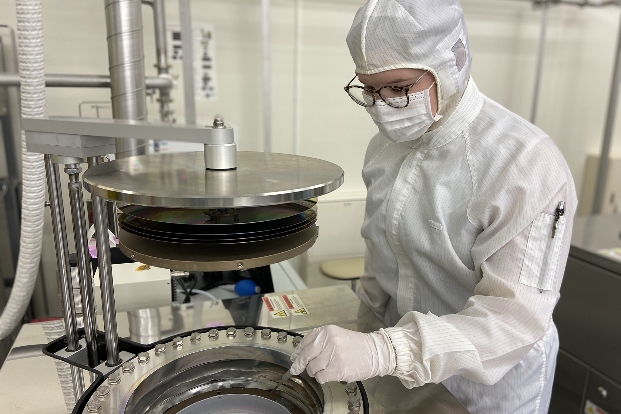 Person wearing white personal protective equipment works with laboratory equipment. 