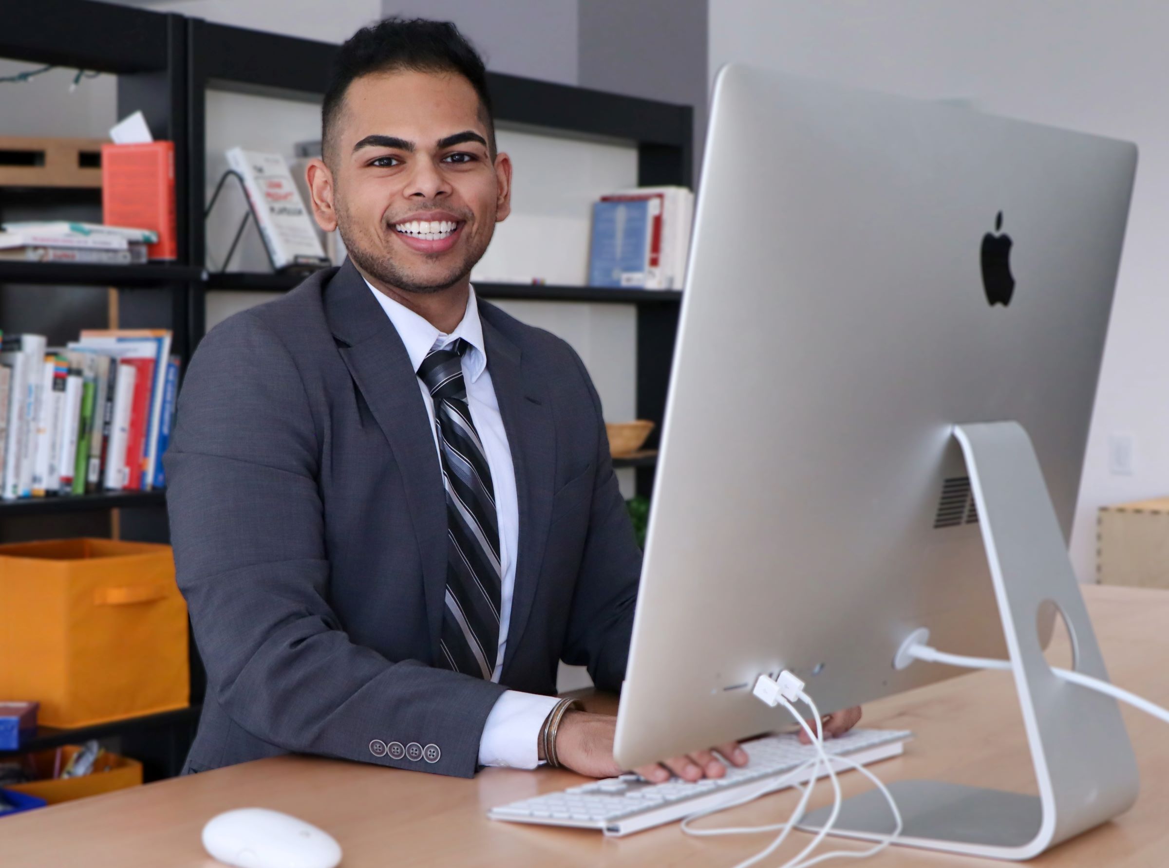 smiling person seated at desk with laptop