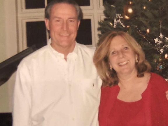 Bob and Denise Rohrbach standing in front of a Christmas tree.