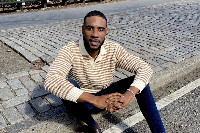 Young Black man sitting on a curb dressed in business casual clothing