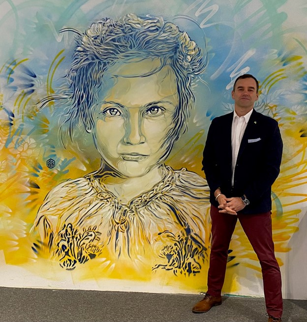 A man standing in front of a colorful painting of a child