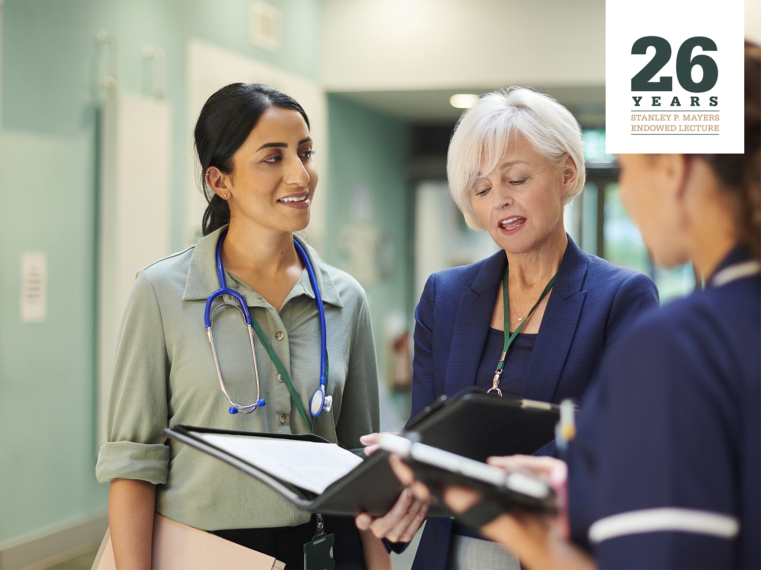 Three female medical professionals conversing with "26 years Stanley P. Mayers Endowed Lecture" logo in the corner.