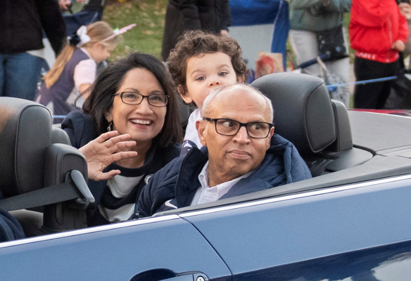 Neeli and Venkat Bendapudi wave from the back of a car in Penn State's homecoming parade