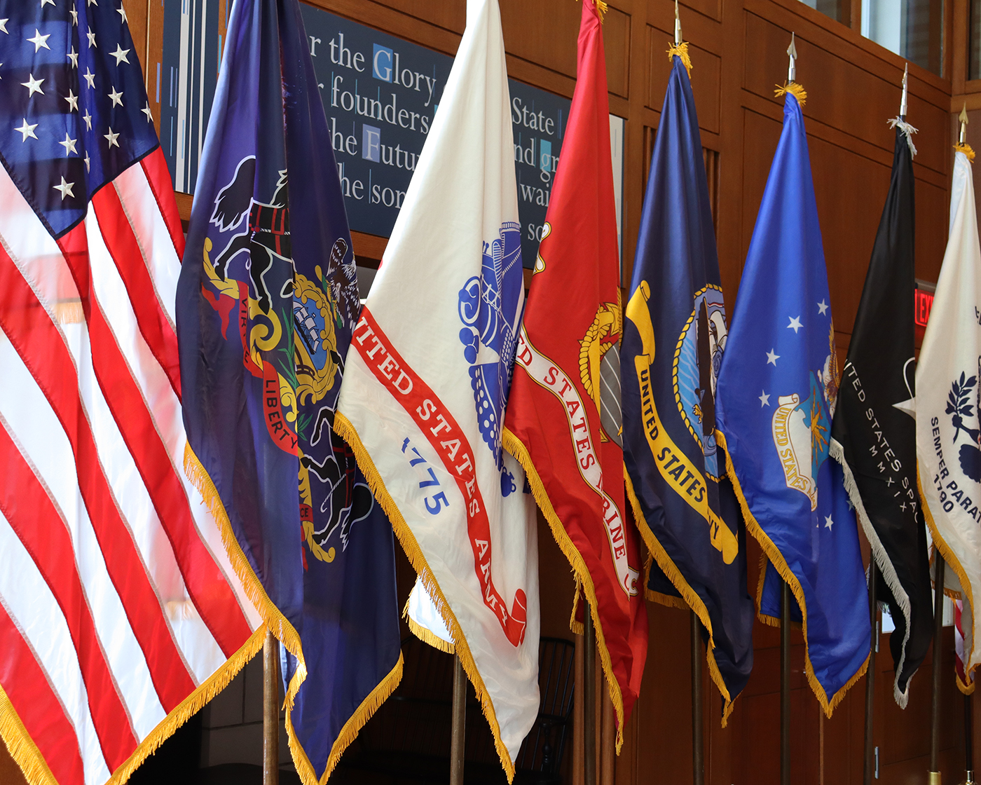 A line of of the American flag and flags of the U.S. Armed Forces.