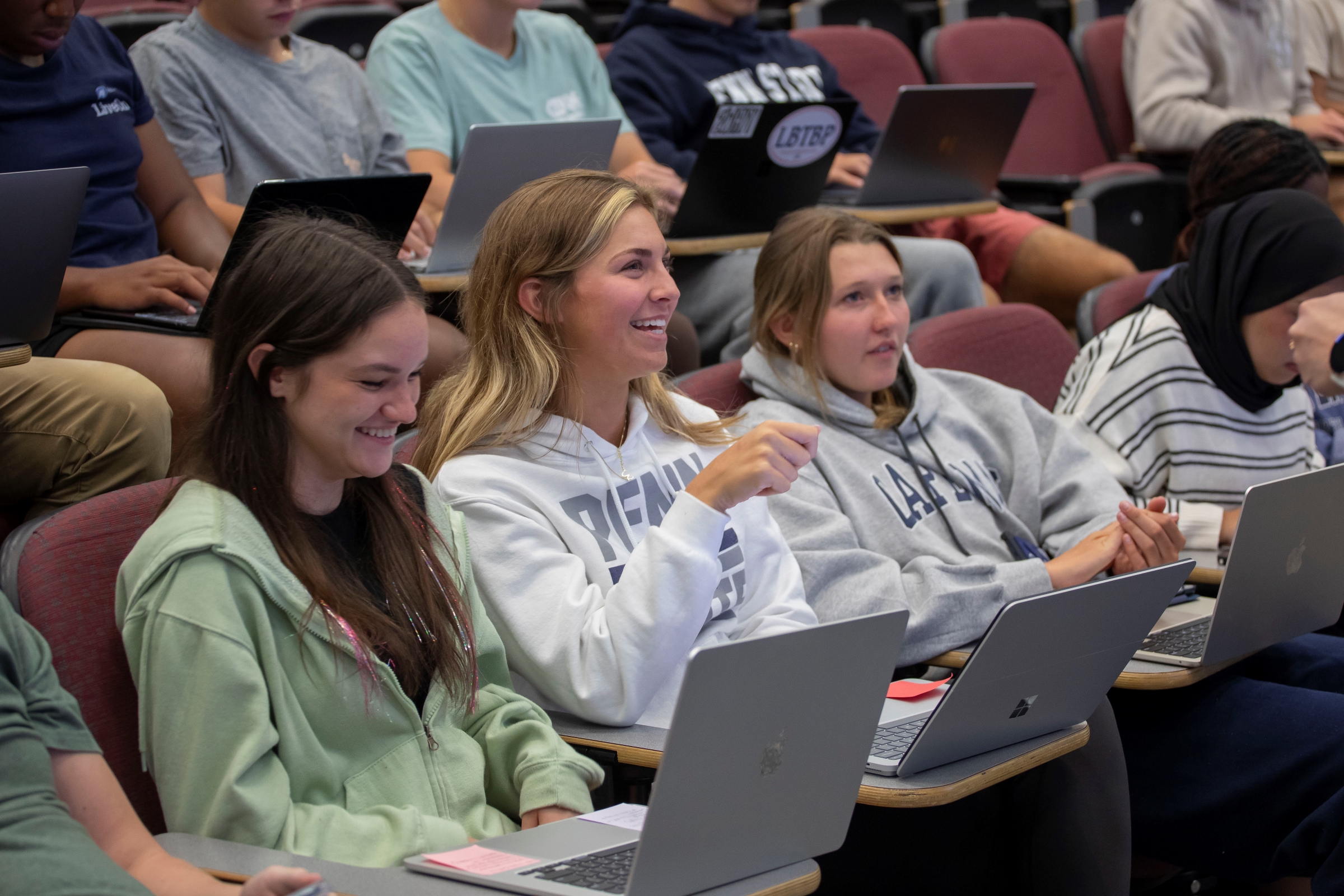 students with laptops in large classroom