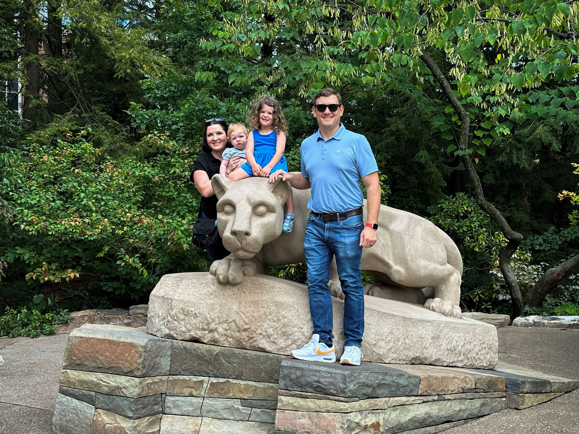 family of four poses on statue of lion