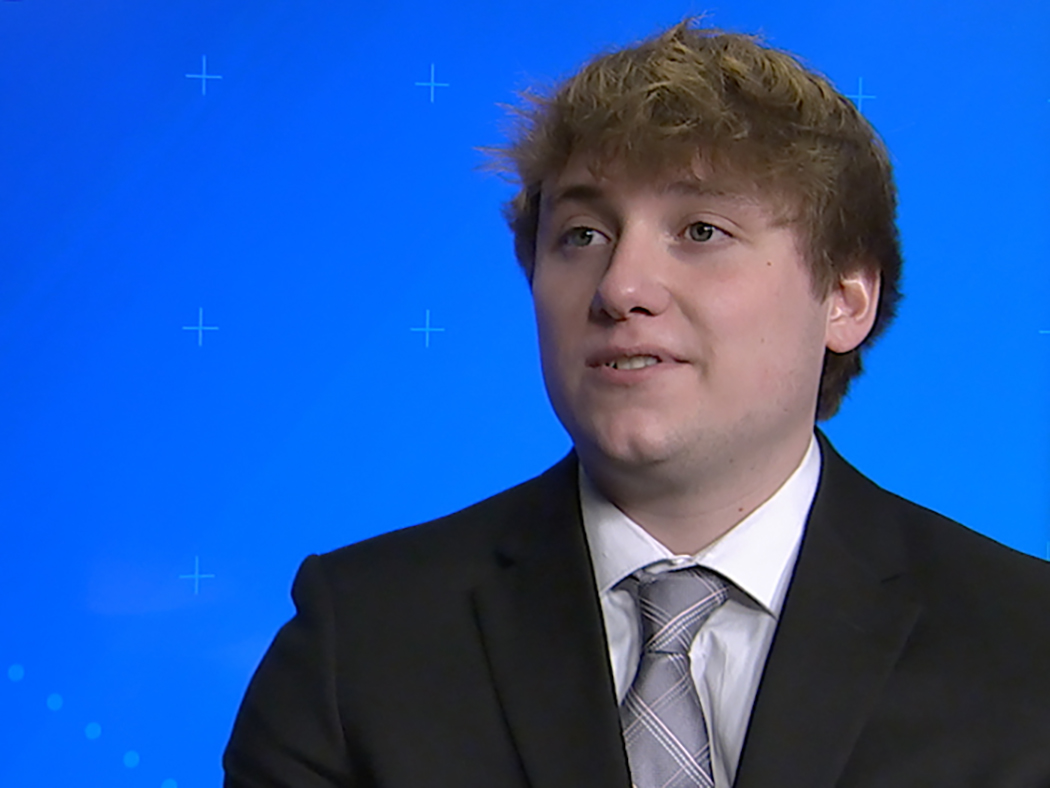 Smiling brown haired young man in front of blue background