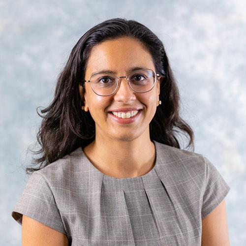 smiling person with long dark hair and glasses