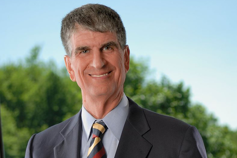 Older white male with gray hair and a suit smiling