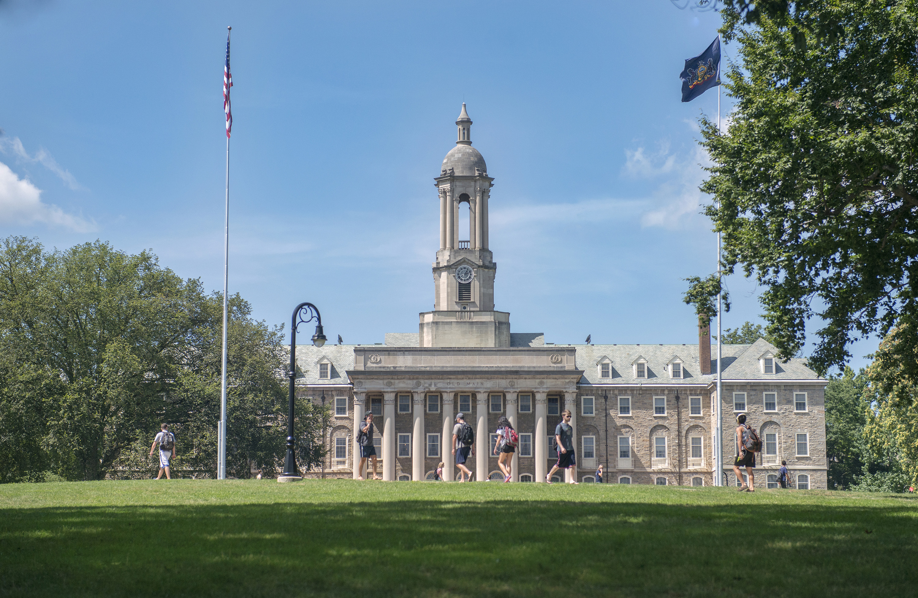 Exterior image of Old Main building at Penn State University Park with flag poles in the foreground