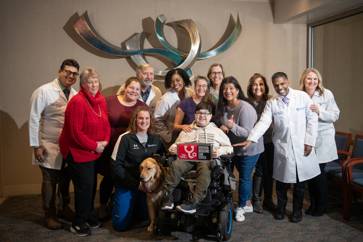 A pediatric muscular dystrophy care team poses with a patient and their family for a photo