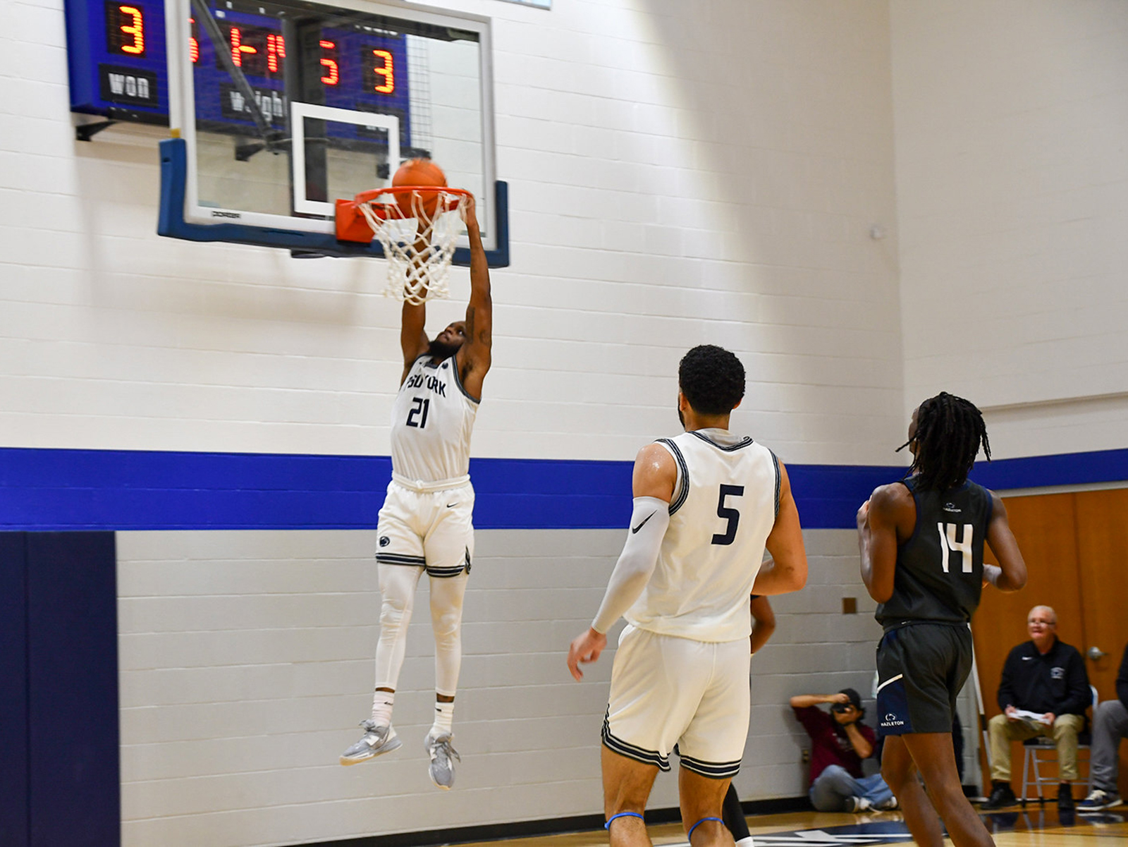 African American basketball player making a slam dunk at the basketball ney, two players watch