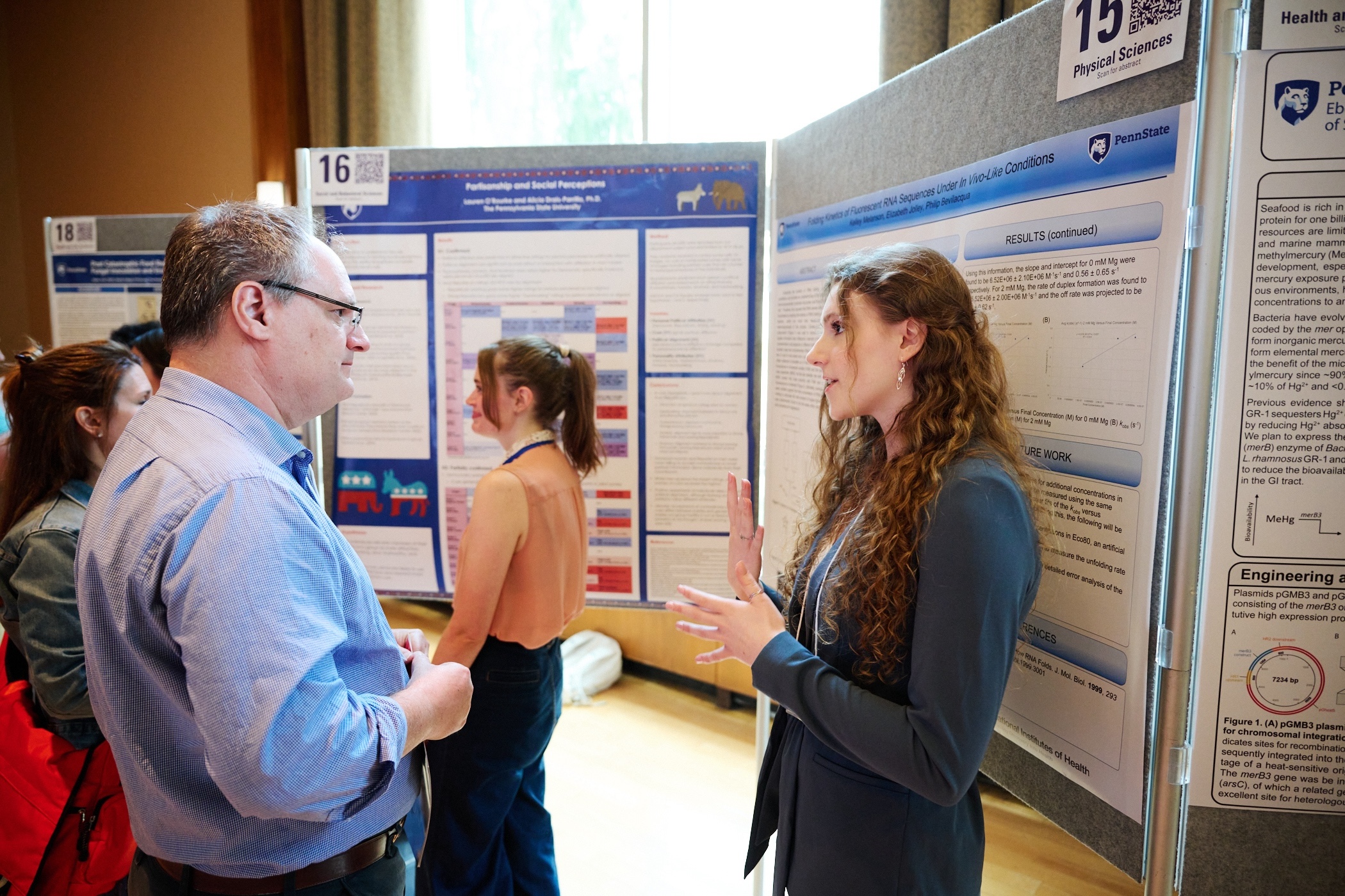 Faculty judge hearing explanation from student presenter in front of a research poster