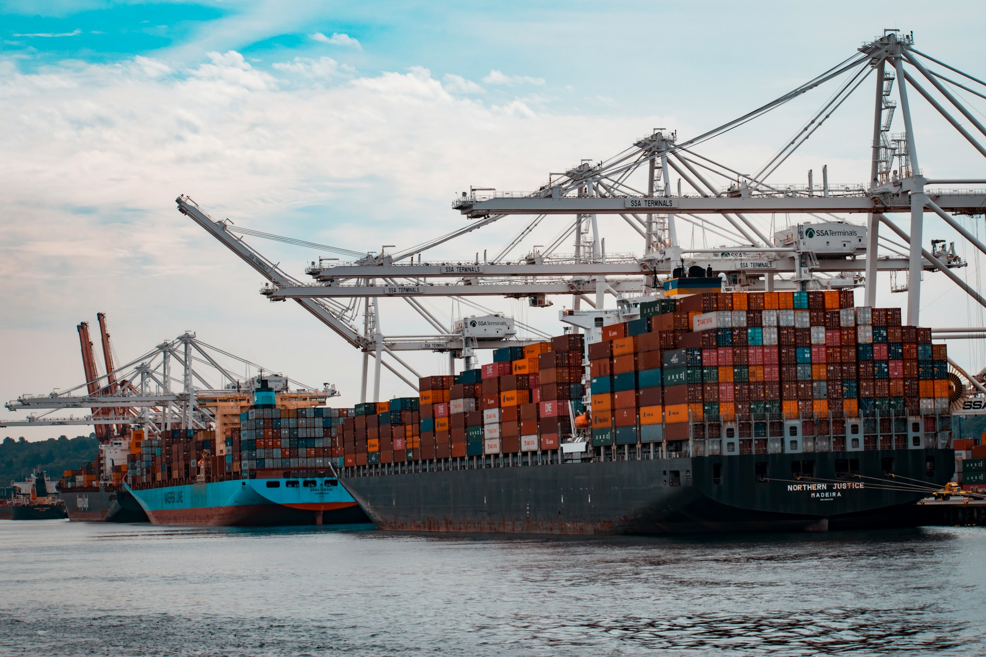 Cargo ships docked at a pier during the day. 