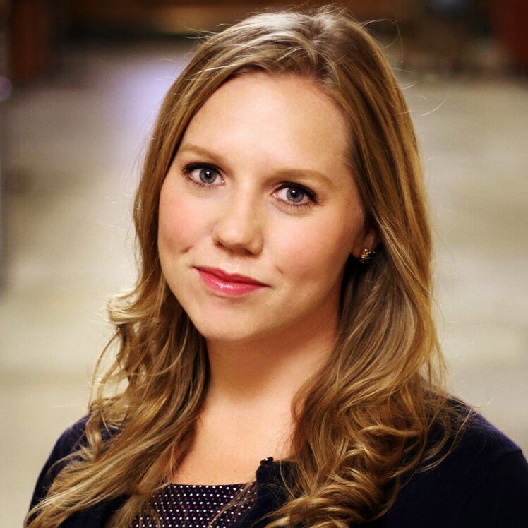 Headshot of Erika Crable, a white woman with long, dark blonde hair and blue yes wearing a dark top.