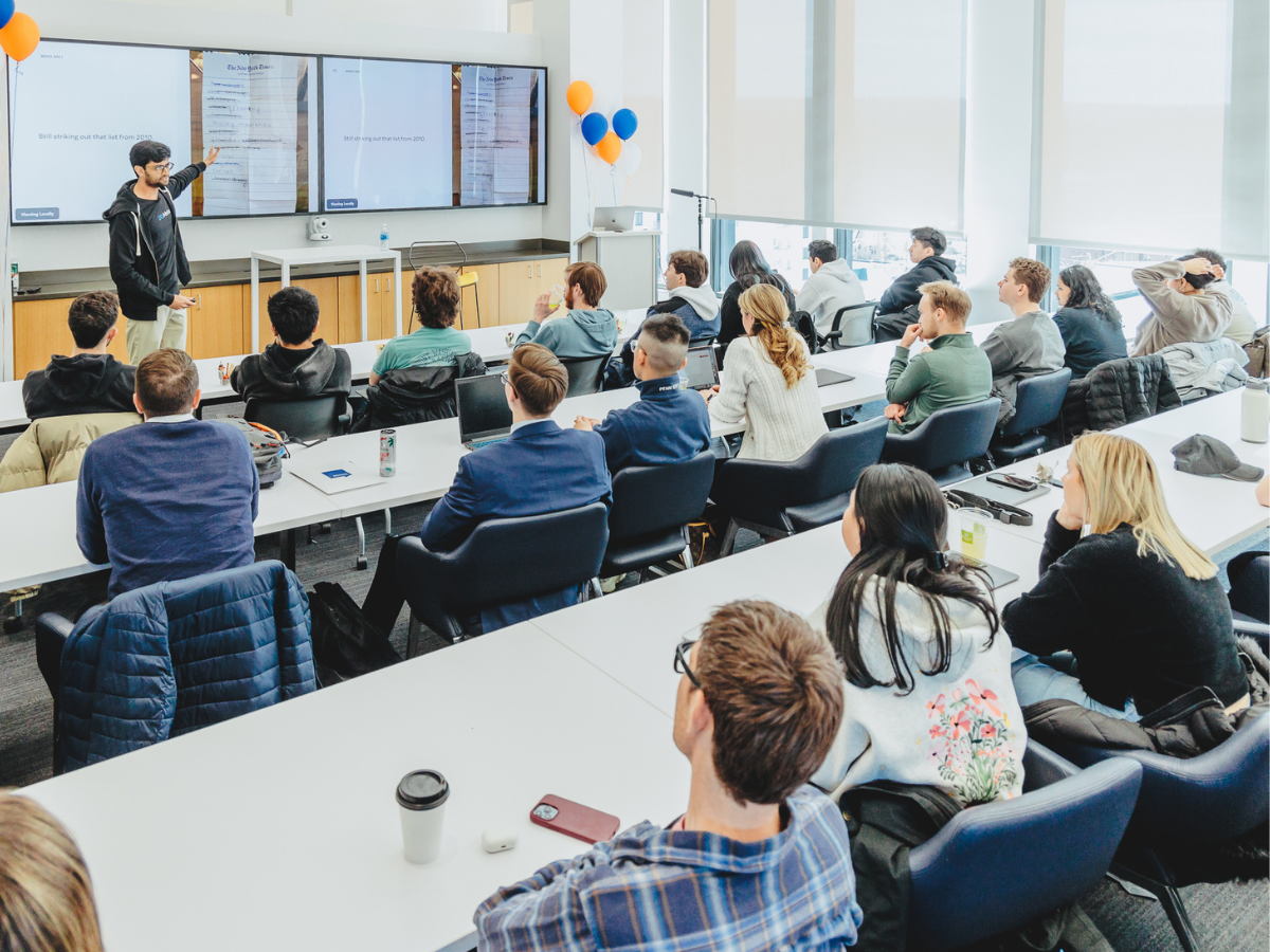 Students listen to Rajesh Rangarajan, who is standing in front of a screen