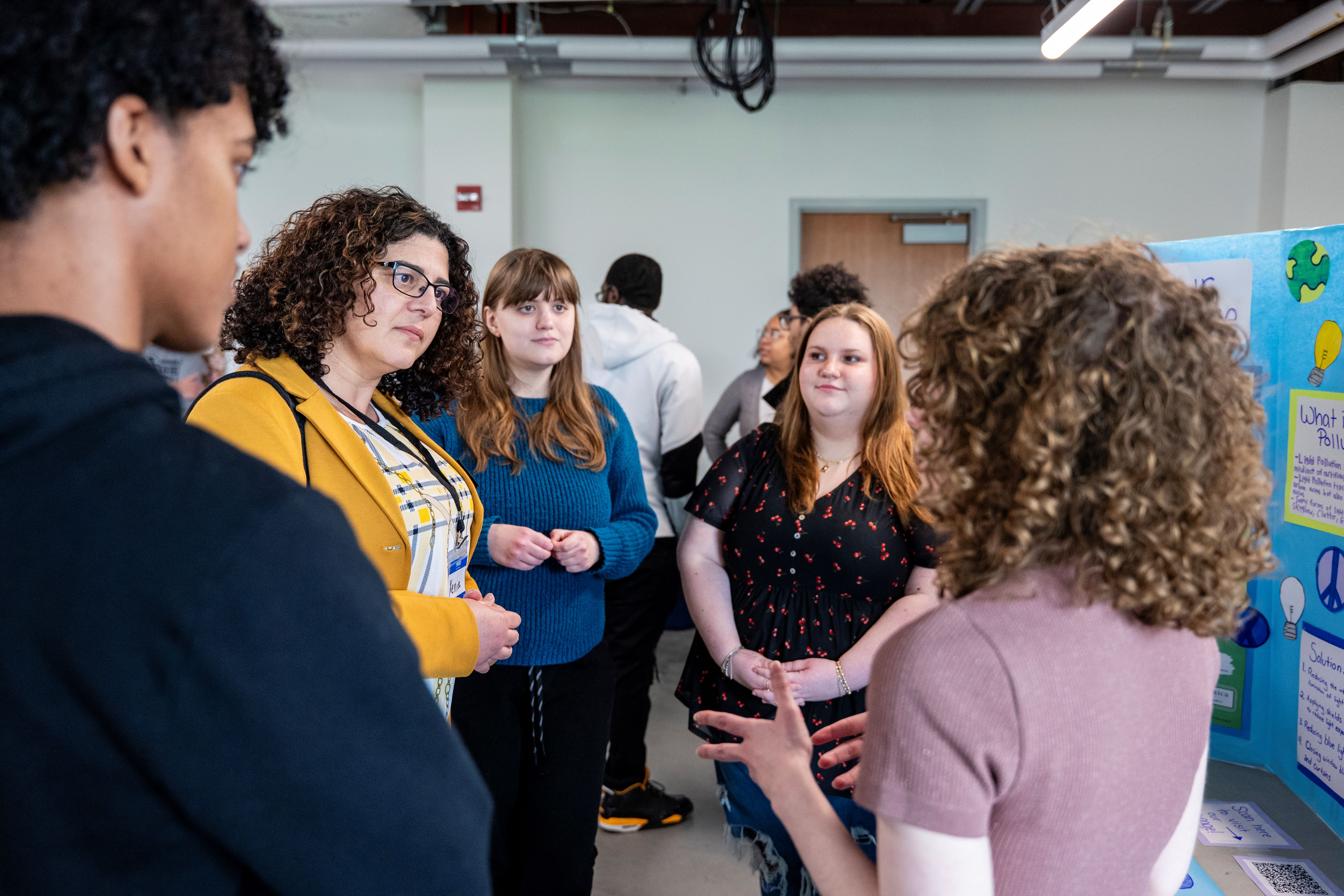 A group of people talking about a poster project at a symposium.