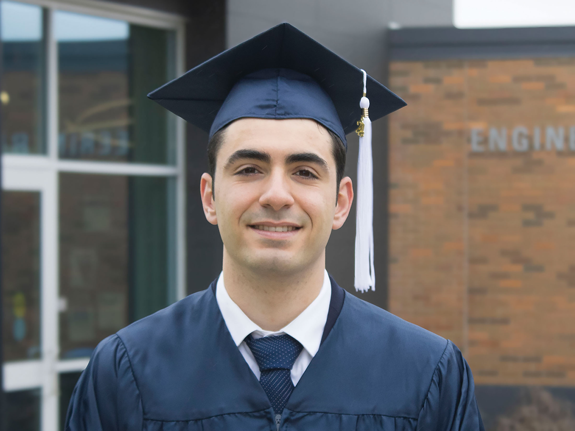 Mechanical engineering student marshal Antonio Pugliese smiles in front of Engineering Building. 