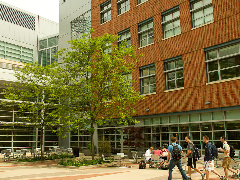 A photo of four students walking in the Business Building courtyard