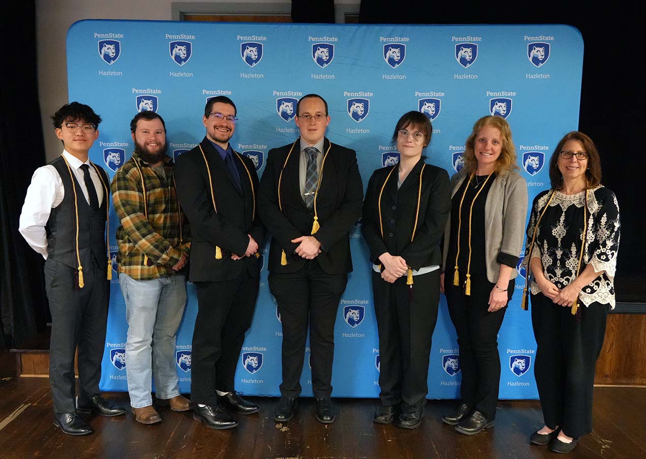 Seven inductees lined up in a row in front of a light blue backdrop 